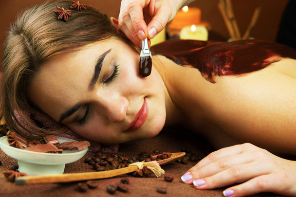 Usmívající se krásná žena v lázeňském salonu s procedurou čokoládové terapie s lázeňským specialistou - Fotografie, Obrázek