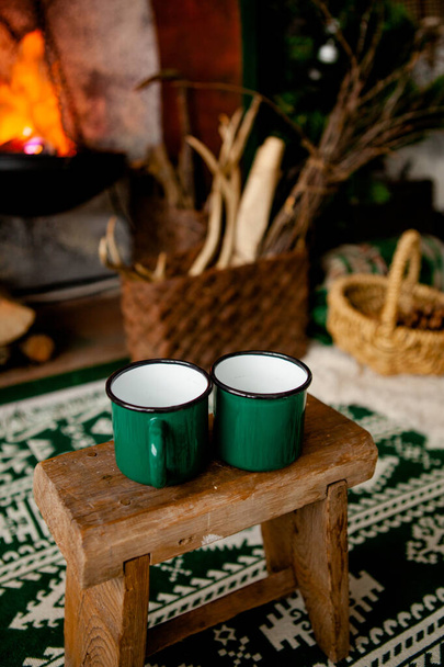 two cups stand on a stool against the background of the hearth in the cottage. Winter theme - Foto, Bild