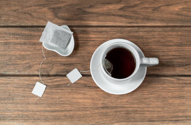 Cup of hot tea with a tea bag for boiling wooden background top view - Foto, afbeelding