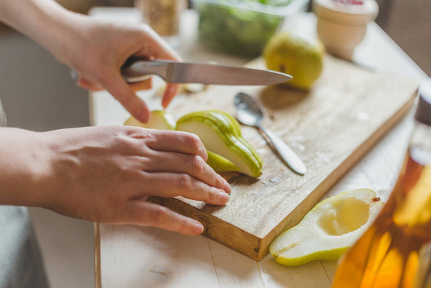Cortar peras en una ensalada en una tabla de madera - receta casera - manos de ama de casa - rural
 - Foto, imagen