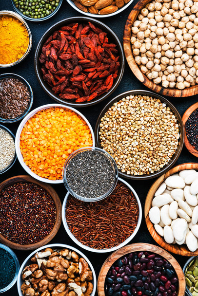 Superfoods, legumes, nuts, seeds and cereals selection in bowls on grey background. Superfood as chia, spirulina, beans, goji berries, quinoa, turmeric, mung bean, buckwheat, lentils, flax seed, wild rice and almond. Copy space, top view - Valokuva, kuva