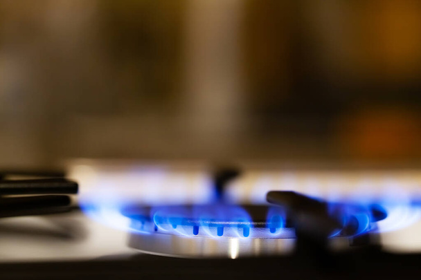 Simple burning gas kitchen stove, burner macro, extreme closeup, shallow depth of field. Clear blue butane flame, cooking, copy space, side view abstract blurry background - Photo, Image
