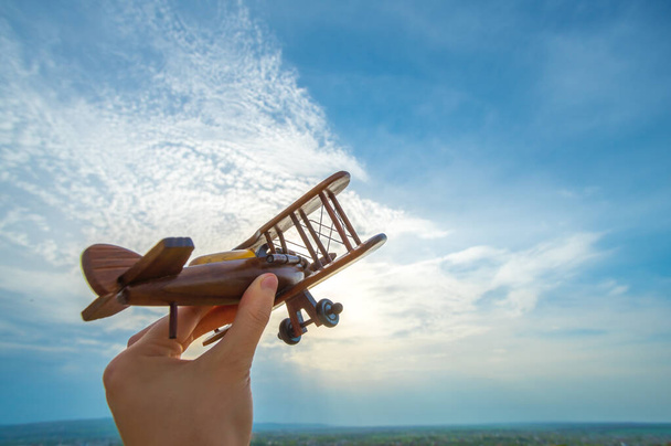 The hand with a wooden plane on the blue sky background - Photo, Image