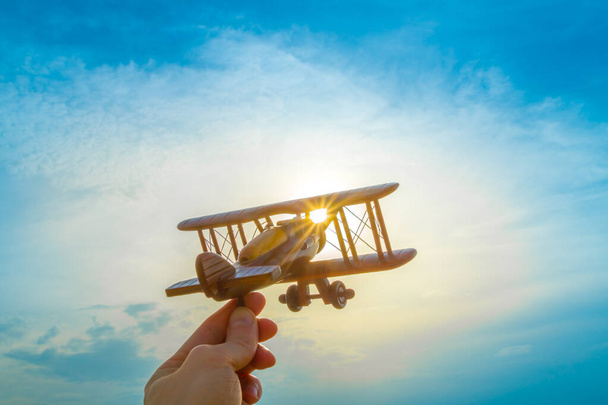 The hand with a wooden plane on the background of the sunset - Photo, Image