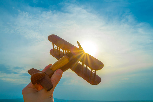 De hand met een houten vlak op de achtergrond van de zonsopgang - Foto, afbeelding