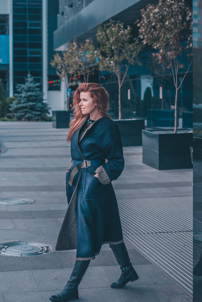 Confident attractive modern elegant woman in a long coat walks around the city - Foto, afbeelding