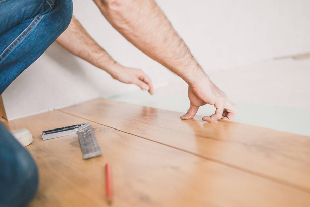 The hands of the master in the process of installing laminate flooring - Foto, afbeelding