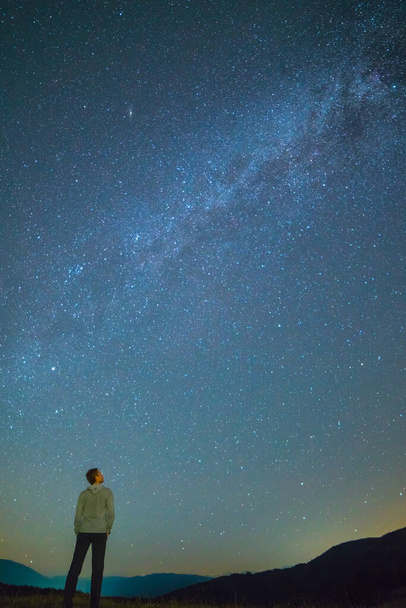 L'homme se tient debout et regarde le ciel avec des étoiles. nuit
 - Photo, image