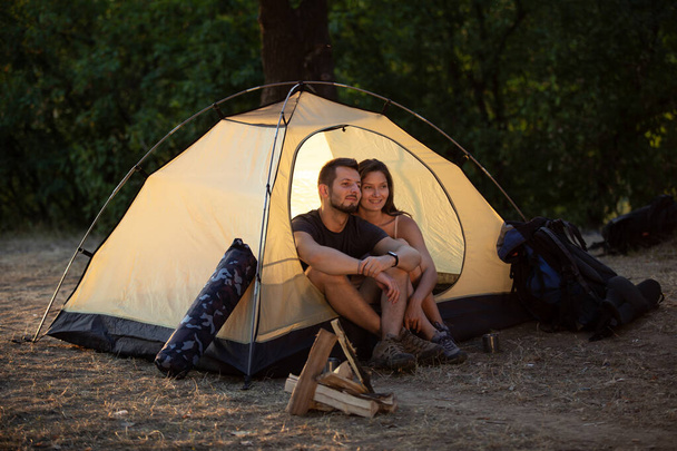 A man and a woman are sitting in a tent at sunset. Honeymoon in the hike - Fotografie, Obrázek