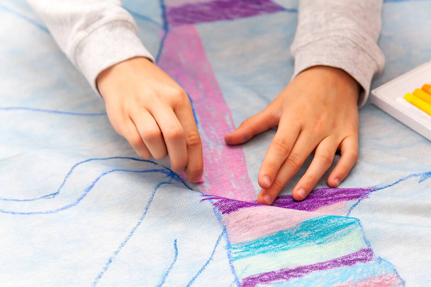 Simple kids hands drawing with precision on a huge canvas using oil pastels, coloring detail, closeup. Diy, children and art, creativity and creating, art classes circle activity abstract concept - Photo, Image