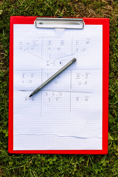 Team game paper scoreboard a pen and a holder laying on the grass outside. Numbered team results, notes written on paper, outdoor group activities and group sports simple abstract concept, nobody - Photo, Image