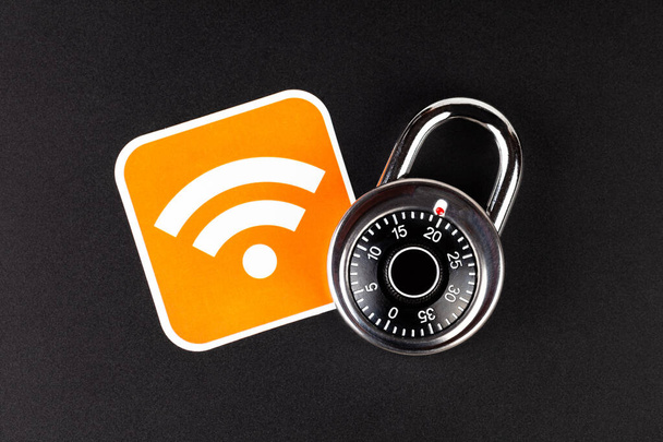 WiFi wireless network security simple abstract concept. Wifi Connection signal symbol and a coded padlock laying on black background. Securing, mobile internet data safety in public hotspots, hacking - Photo, Image
