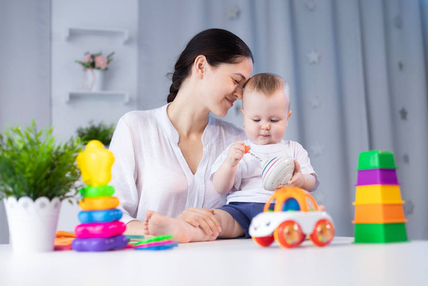 Mom and little son are playing with different developing toys in a bright children's room - Foto, Imagem