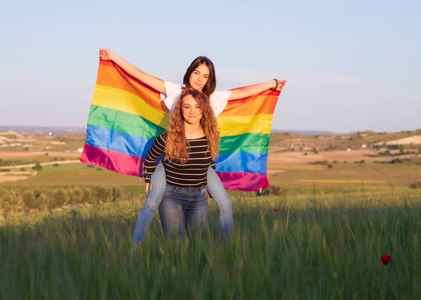 λεσβιακό ζευγάρι με γκέι σημαία υπερηφάνειας στο δρόμο - Φωτογραφία, εικόνα