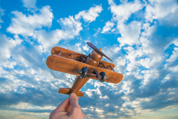 Ręka uruchamia drewniany samolot na tle błękitnego nieba - Zdjęcie, obraz