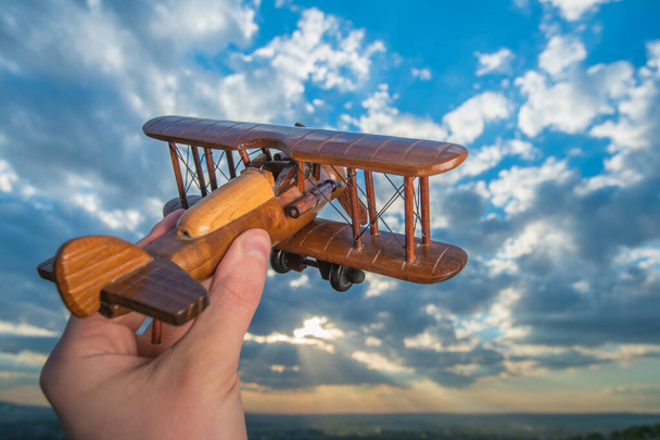 The hand hold wooden plane on the background of a blue sky - Photo, Image