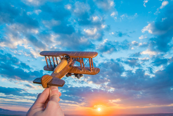 Ручний запуск іграшкового літака на тлі сходу сонця
 - Фото, зображення