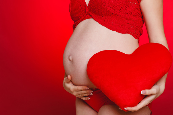 Young woman is pregnant, on a red background - Photo, Image