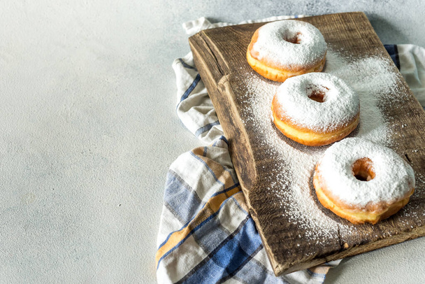Donuts caseiros doces exuberantes polvilhados com açúcar em pó em um fundo de madeira
 - Foto, Imagem