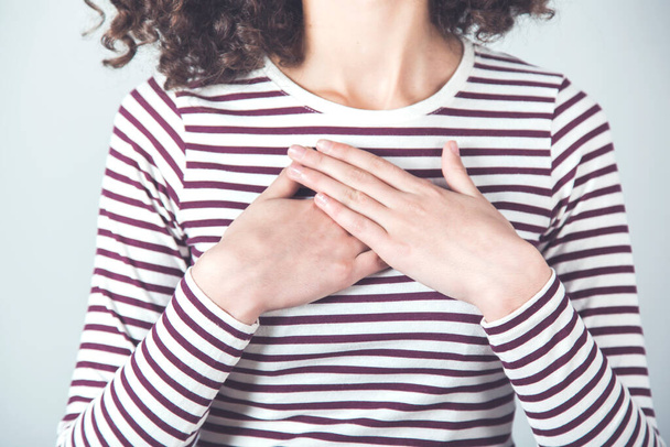 woman hand on heart on the gray background - Foto, Imagem