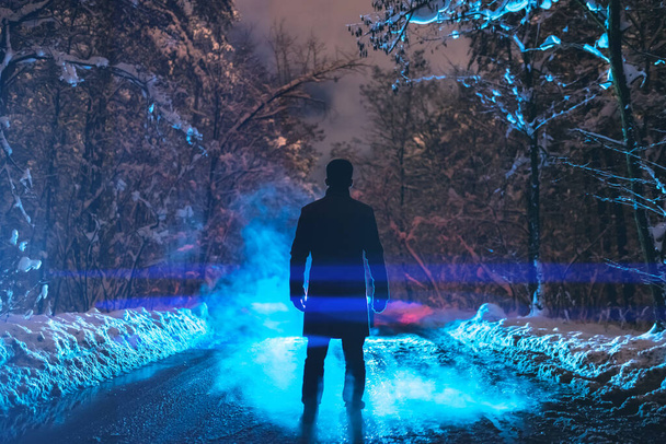 El hombre está parado en un camino forestal en el fondo de un humo. noche noche tiempo
 - Foto, Imagen