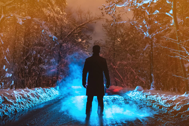 El hombre está parado en un camino forestal sobre el fondo de humo. noche noche tiempo
 - Foto, imagen