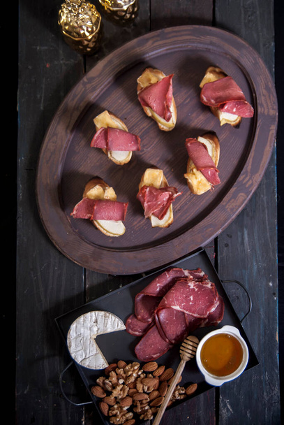 Bread Brie Cheese and Rolled Pastrami with Nuts and Honey on a Wooden Tray - Foto, immagini