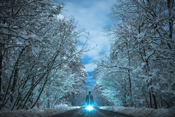 O homem está em uma estrada nevada em um fundo claro brilhante. noite noite tempo
 - Foto, Imagem