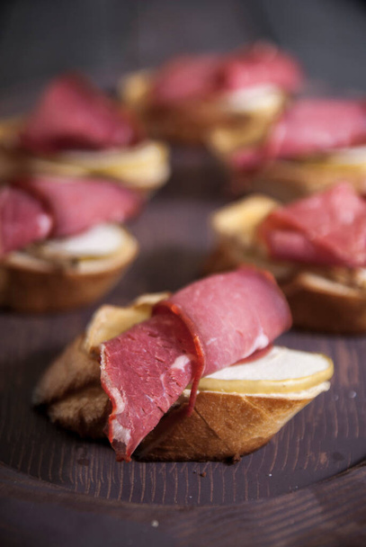 Bread Brie Cheese and Rolled Pastrami with Nuts and Honey on a Wooden Tray - Photo, Image