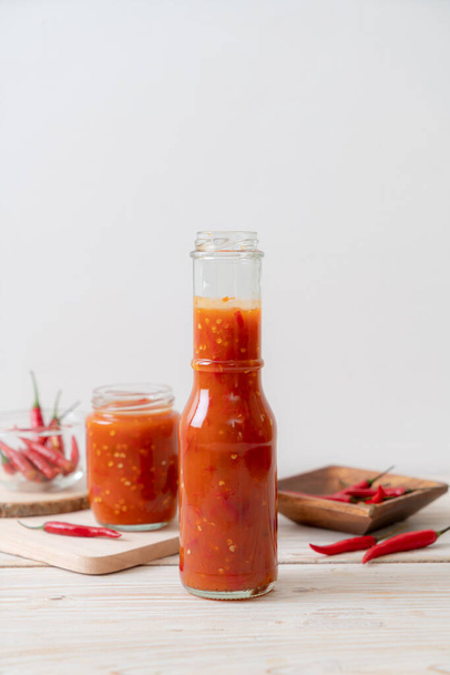 chilli or chilli sauce in bottle and jar on wwod background - Foto, Imagen