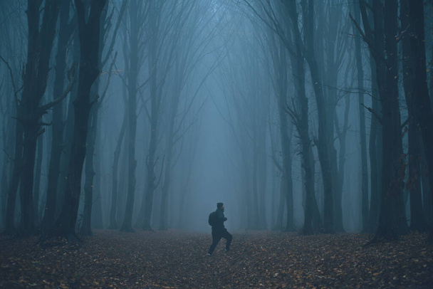 Mann verirrte sich in gespenstischem Nebelwald zwischen hohen Bäumen - Foto, Bild