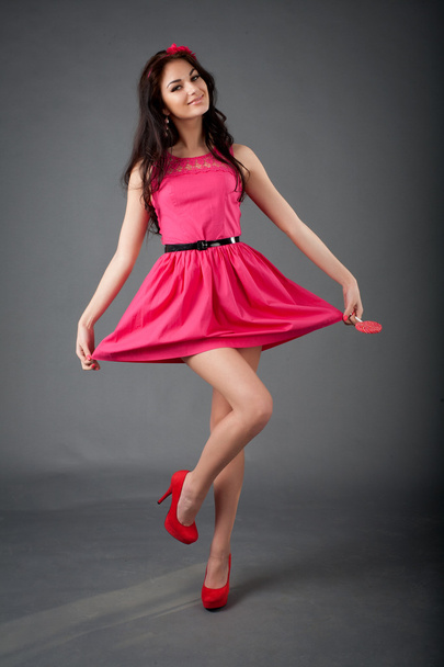 το όμορφο μοντέλο σε ένα ροζ φόρεμα με το γλειφιτζούρι στο χέρι - Φωτογραφία, εικόνα
