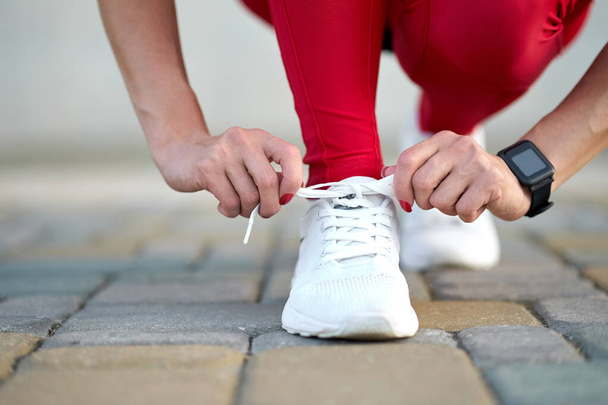 Close-up van vrouwelijke benen in stijlvolle rode sport leggings en trendy witte sneakers. Actieve slanke vrouw op een training. Maak je klaar om te beginnen..                                - Foto, afbeelding