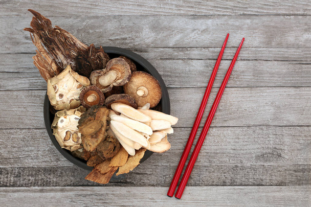 Erbe cinesi utilizzate nella medicina tradizionale a base di erbe antiche con bacchette rosse su sfondo in legno rustico
. - Foto, immagini