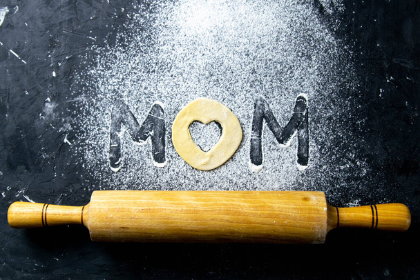 Mather Day Konzept. Word-Mom aus Mehl und Teig auf dunklem Hintergrund. Top-Ansichten, Nahaufnahme. - Foto, Bild