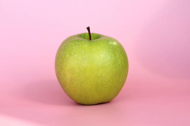 Green apple on a pink background. Juicy ripe beautiful fruit - Fotoğraf, Görsel