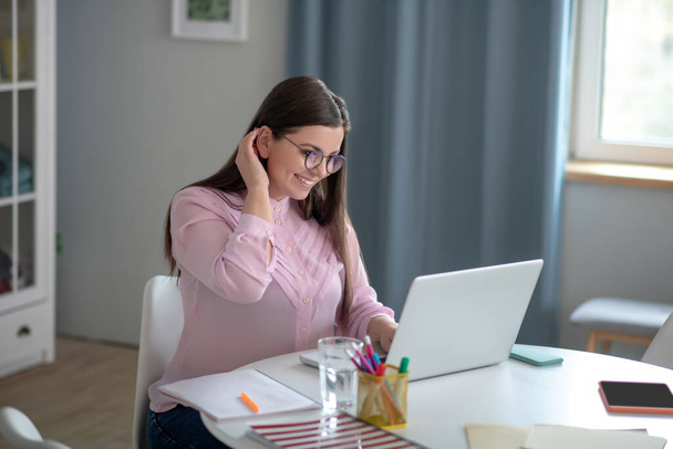 Woman in a pink blouse wearing eyeglasses having a video conference - Foto, Imagem