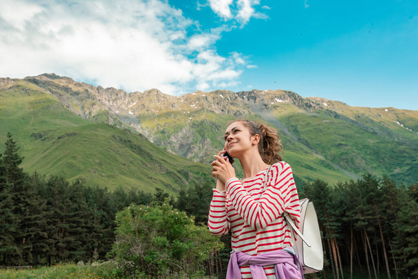 Freedom girl traveler woman standing with phone in hands and enjoy a wonderful Caucasian mountains - Foto, imagen