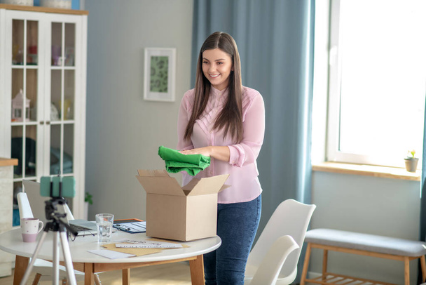 Dark-haired young woman taking green pants out of box - Fotoğraf, Görsel