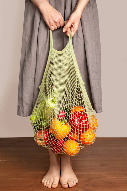 Girl holds a string bag with vegetables and fruits. The concept of green shopping and good nutrition. Environmental Protection. Delivery of products. - Foto, Imagem