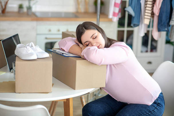 Dark-haired young woman sleeping on the boxes - 写真・画像
