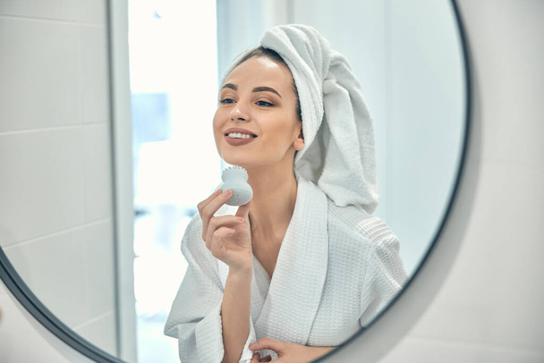 Caucasian happy lady doing massage for her face in bathroom - Photo, Image
