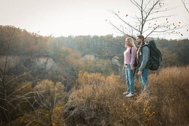 Couple of tourists admiring the sunset standing on the edge of a cliff holding hands - Fotografie, Obrázek