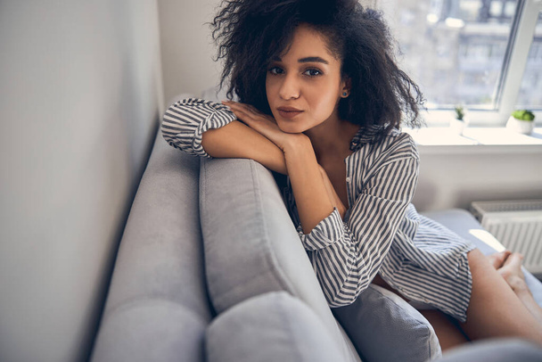 Girl with curly hair sitting on the sofa - Фото, изображение