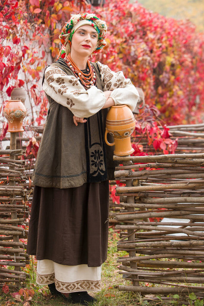 Beautiful girl in national dress. With an ancient clay pot. Antique clothing of the late 19th century. Beautiful dress and skirt on a woman. Beautiful autumn and leaves. Clothing of the late 19th - Photo, Image