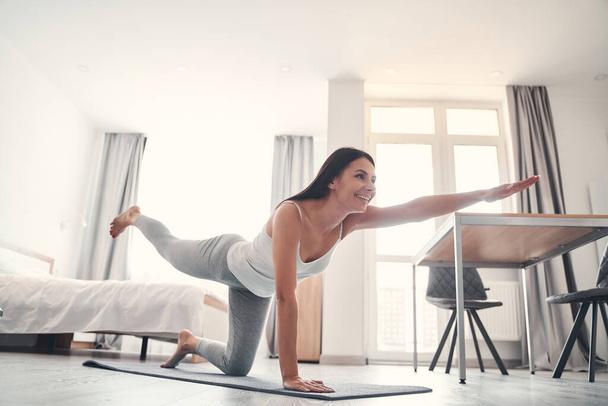 Joyful brunette girl keeping balance during training - Valokuva, kuva
