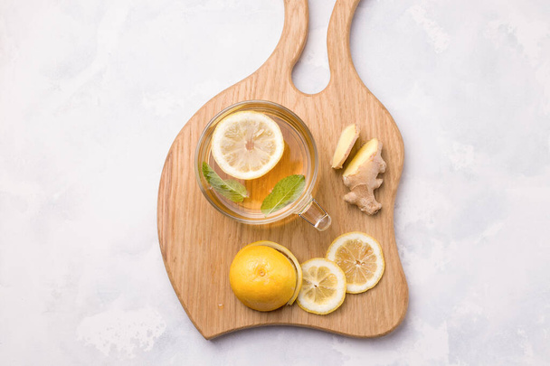 Drink with lemon, mint and ginger on a concrete background next to the ingredients. Virus protection - Foto, Imagem