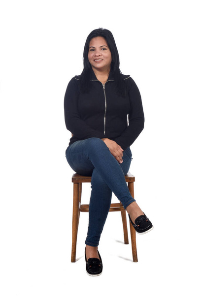 портрет жінки, що сидить на стільці на білому тлі, дивлячись на камеру
 - Фото, зображення