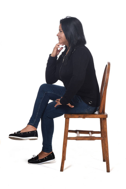 retrato de una mujer sentada en una silla en fondo blanco, las piernas cruzadas y la mano en la barbilla
 - Foto, imagen