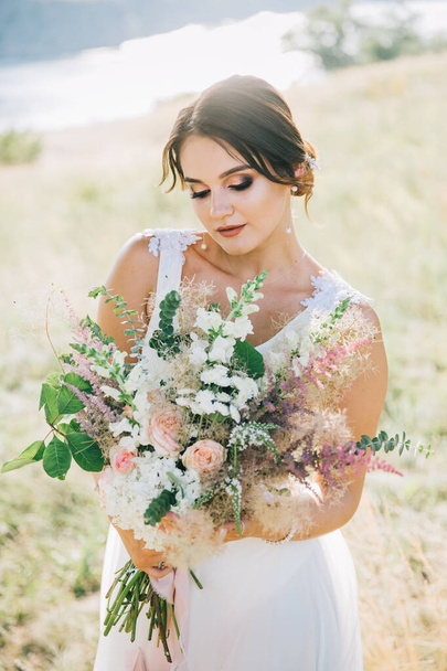 Nevěsta v luxusní bílé svatební šaty v přírodě při západu slunce - Fotografie, Obrázek